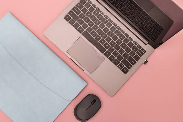 istock Top view of white working table with modern laptop, blue leather case for personal computer and wireless mouse. Work space for school or office. Template and Copy space. Flat lay. 1179351127