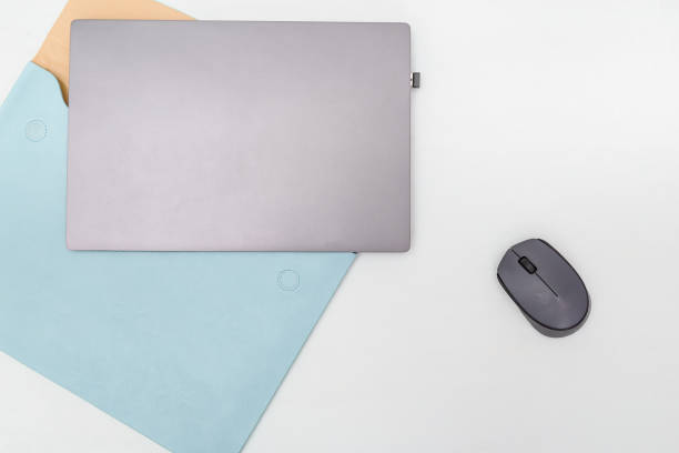 istock Top view of white working table with modern laptop, blue leather case for personal computer and wireless mouse. Work space for online education, for student. Copy space. Flat lay. 1179351128