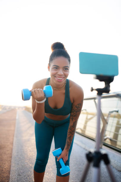 istock Woman doing exercises with barbells while filming blog 1179352617