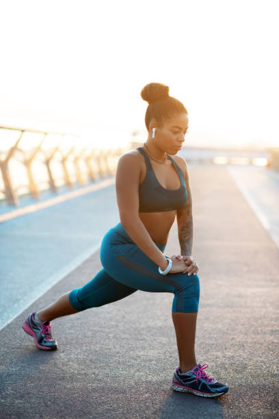 giovane donna oversize che allunga le gambe dopo aver fatto jogging - strutting foto e immagini stock