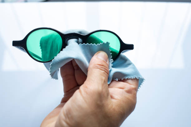istock Woman's right hand cleaning black sunglasses by microfibre cleaning cloths, On white background, Close up & Macro shot, Selective focus, Optical concept 1179353467