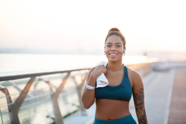 istock Beaming woman holding towel while walking after run 1179353480