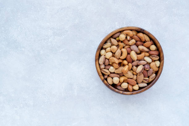 istock Roasted salted mixed nuts in wooden bowl. Top view with space for text 1179363108