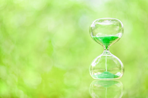Time management, deadline and countdown concept : Green sand fall down in a clear glass sandclock or hourglass over green bokeh space, depicts flowing or passing of time from past, present to future Time management, deadline and countdown concept : Green sand fall down in a clear glass sandclock or hourglass over green bokeh space, depicts flowing or passing of time from past, present to future approaching stock pictures, royalty-free photos & images