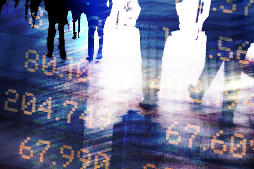 Abstract image of traders in financial district with trading screen data, light reflections and blurred movement.