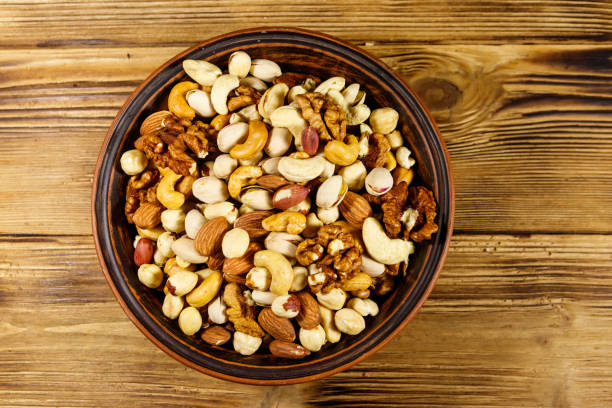 istock Mixed nuts on wooden table. Walnuts, pistachio, almond, peanut, cashew, hazelnut in ceramic bowl. Healthy eating concept. Top view 1179372231