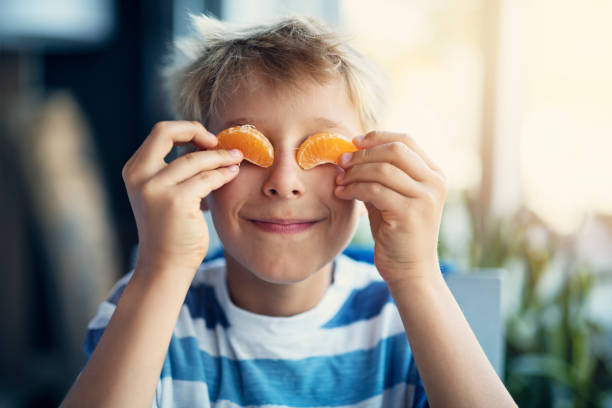 porträtt av en rolig liten pojke äta orange - carpel bildbanksfoton och bilder