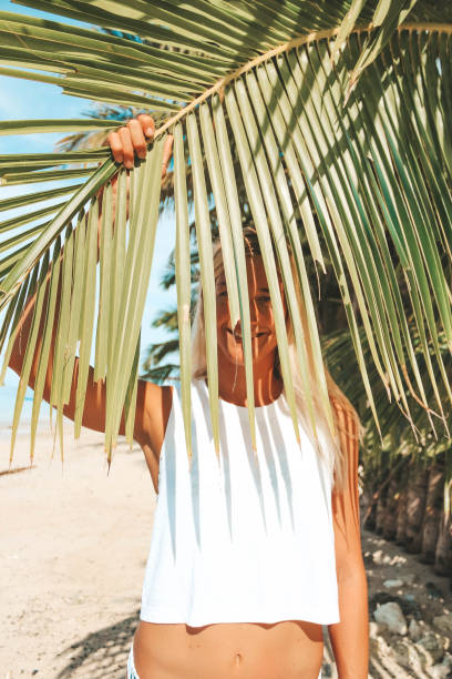 istock Woman hiding behind a palm tree leaf 1179383518