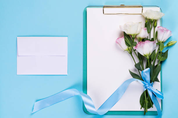 istock Minimal composition with a Eustoma flowers in an envelope with clipboard on a blue background, top view. Valentines day, birthday, mother or wedding greeting card 1179383812