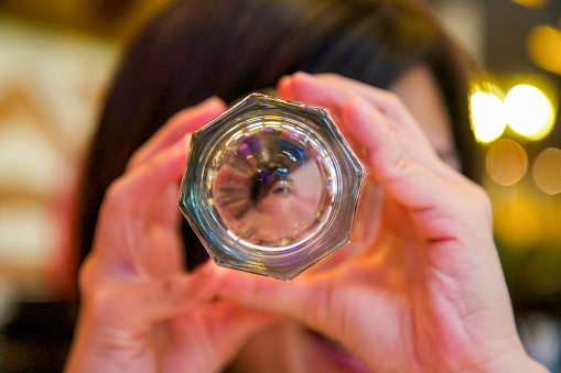Abstract photo of a woman peeking through a glass bottle.
