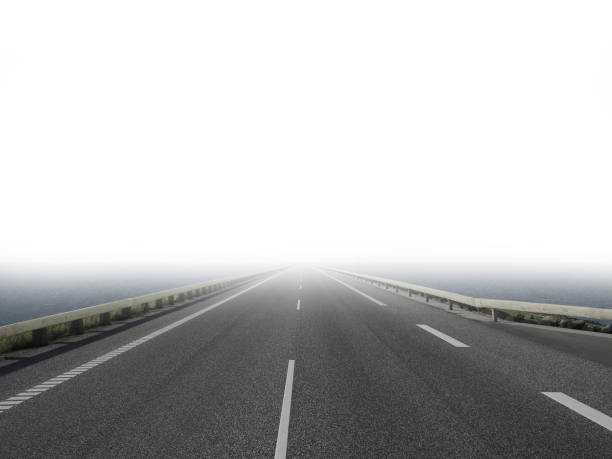 lonesome empty road leading straight forwards through the water and gets lost in the fog