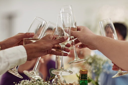 Cropped shot of a group of wedding guests toasting with wine at a wedding reception