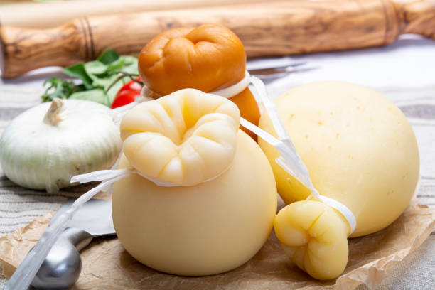 provolone italiano o provola caciocavallo formaggi duri e affumicati in forma di lacrima serviti su carta vecchia da vicino - provolone foto e immagini stock