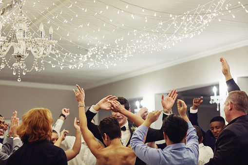 Shot of a young couple dancing with their friends at their wedding reception