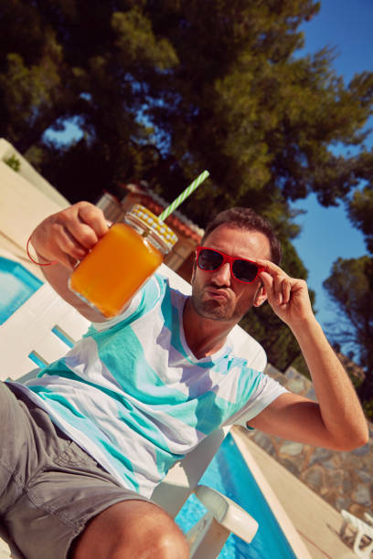 istock Attractive man drinking juice on the swimming pool. Summer concept. 1179395650