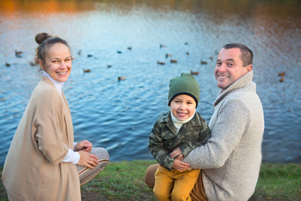 Father, mother and little son feeding ducks