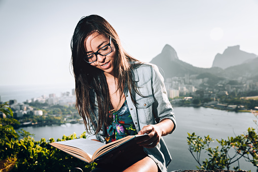 Young Brazilian woman reading a book outdoors at Rio de Janeiro