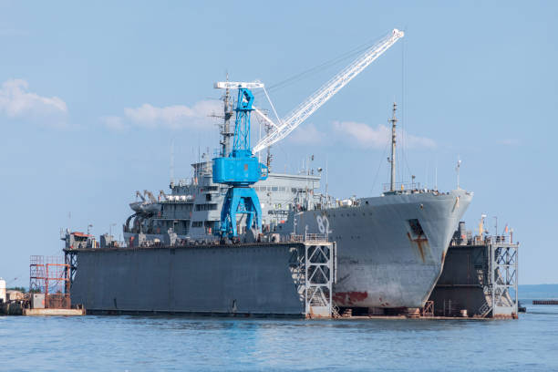 grandes buques de la marina de hierro en el astillero para su reparación. una grúa grande en el astillero. puerto azul del mar - shipbuilder fotografías e imágenes de stock