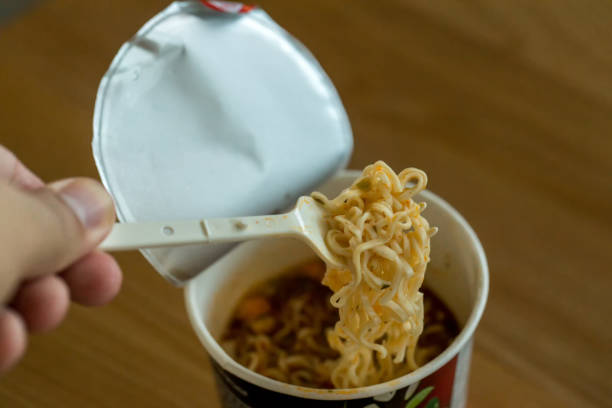 istock Hot noodle Cup. Noodle cup Ready made. Eating Instant Noodles with a Plastic Fork. Junk food Instant noodles are eating the popular food. 1179404558