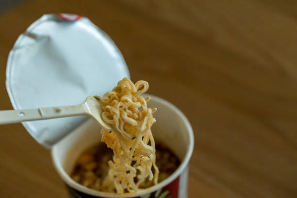 istock Hot noodle Cup. Noodle cup Ready made. Eating Instant Noodles with a Plastic Fork. Junk food Instant noodles are eating the popular food. 1179404576