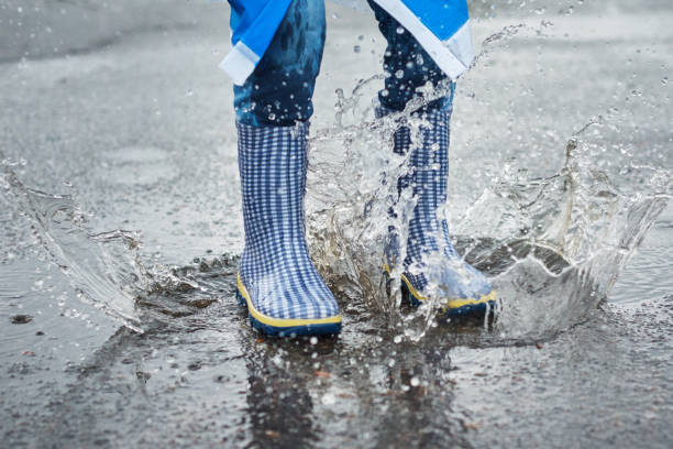 istock child in blue rubber boots jumping over the puddle in the rain 1179405561