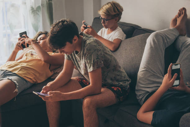 집에서 소파에 앉아 스마트 폰을 사용하여 십대의 그룹. 젊은 소년과 온라인 소셜 스토리를보고 사진과 비디오를 공유하는 소녀. 새로운 트렌드 기술을 즐기는 친구들. 청소년 및 기술 개념 - craving 뉴스 사진 이미지