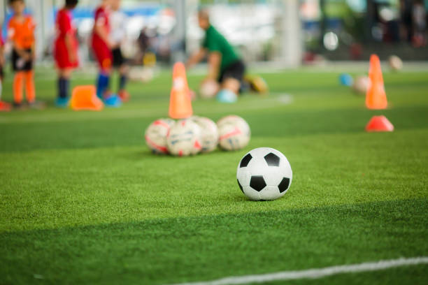 istock Soccer ball on green artificial turf with blurry soccer team training. 1179414172
