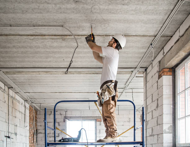 installatore elettricista con uno strumento in mano, lavorando con il cavo in cantiere. - asse di circuito foto e immagini stock