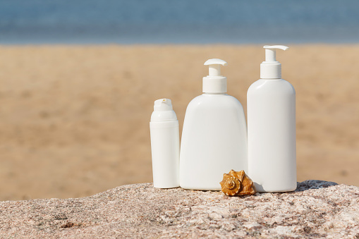 White bottles of cosmetics on the beach