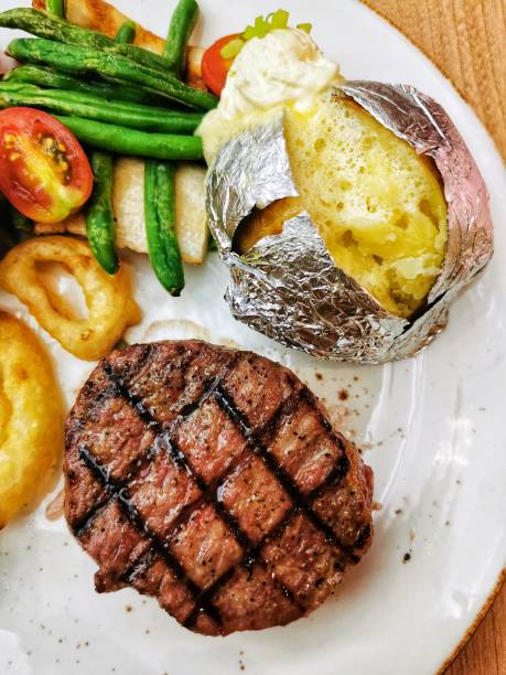 中程度のレアビーフステーキ 穀物飼料オーガニック牛と焼き芋ディナーミールsとミックス野菜 - sirloin steak baked potato beef gourmet ストックフォトと画像