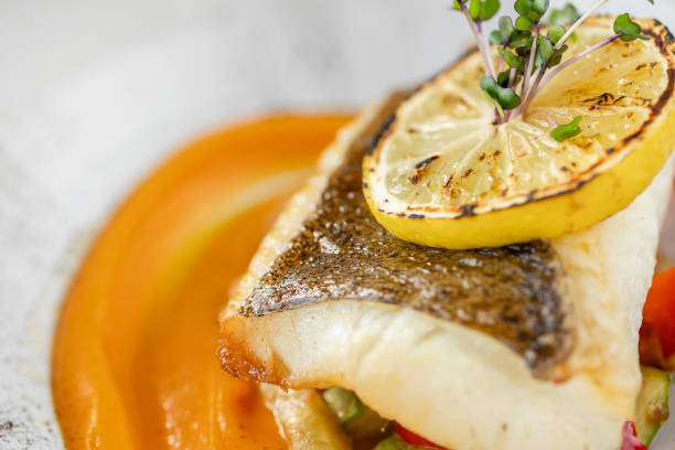 istock Roasted pike perch or cod fish with baked vegetables. Dish decorated with a slice of lemon. Restaurant menu 1179430239