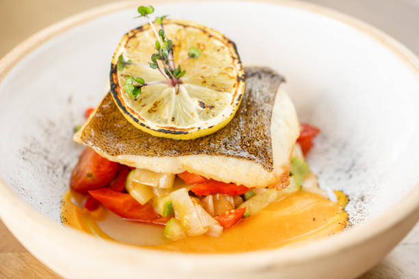 istock Roasted pike perch or cod fish with baked vegetables. Dish decorated with a slice of lemon. Restaurant menu 1179430356