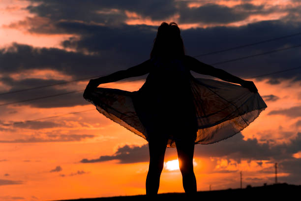 Silhouette of a woman against the background of the setting sun