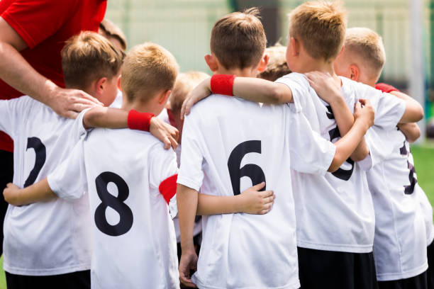 equipo de fútbol juvenil apilando las manos con el entrenador antes de un partido. imagen del equipo deportivo junior con entrenador joven. entrenamiento kids team sports - nivel júnior fotografías e imágenes de stock