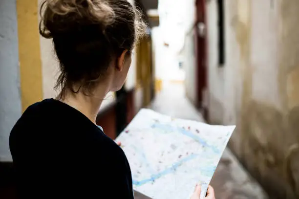 A young tourist is holding a paper map of the place. The photo was taken over her shoulder out of a rear view. I have created this map and own the copyright of the map design shown.