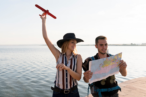 man and woman traveler looking at map.  Traveler holding map in hands and holding airplane in hand. travel and sightseeing concept.