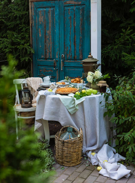 Beautifully decorated summer garden table with apple pies, tea cups, strawberry jam, old Russian samovar Beautifully decorated summer garden table with apple pies, tea cups, strawberry jam, old Russian samovar over the blue door rustic background apple pie a la mode stock pictures, royalty-free photos & images