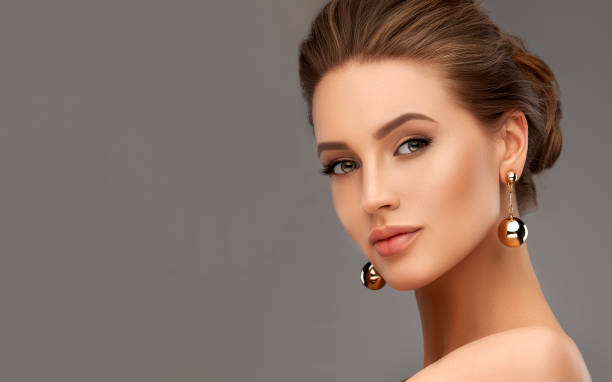 Portrait of beautiful woman with a misty look. Makeup and cosmetic. Portrait of perfectly looking woman dressed in splendid evening makeup. Ripe lips, painted in rose color, long black eyelashes and gilded eyelids. Big golden balls of earrings in her ears. Mystic and misty look in her eyes. female likeness photos stock pictures, royalty-free photos & images