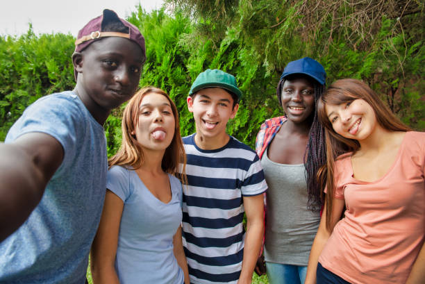 adolescents utilisant les médias sociaux. groupe d'adolescents multiethniques avec des visages drôles prenant un selfie à poster sur les médias sociaux - grimacing male african descent teenage boys photos et images de collection