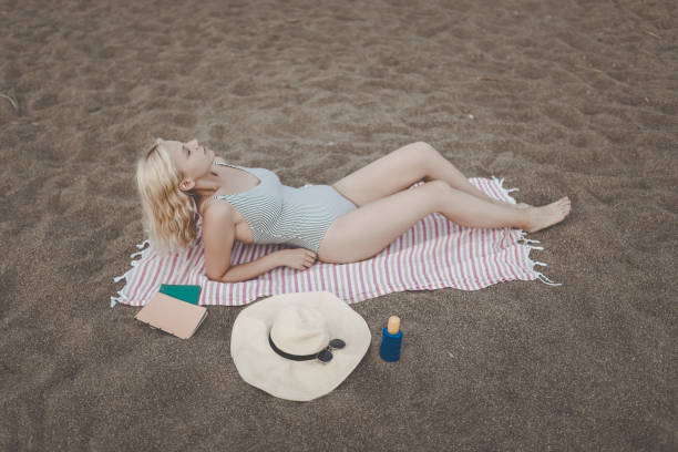 istock blonde woman sunbathing on the beach 1179441966