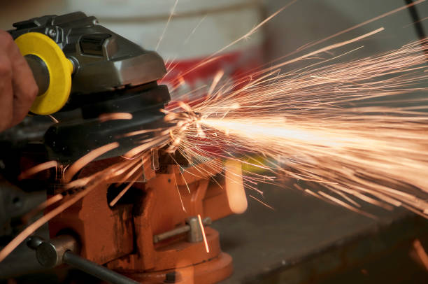 istock Worker in a workshop grinder processes metal, from which hot bright sparks fly in different directions 1179442926