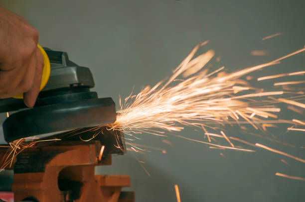 istock Worker in a workshop grinder processes metal, from which hot bright sparks fly in different directions 1179442928