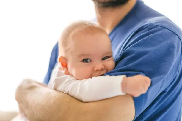 Photo of Satisfied kid in the arms of dad. Divide the responsibilities of caring for a child between spouses