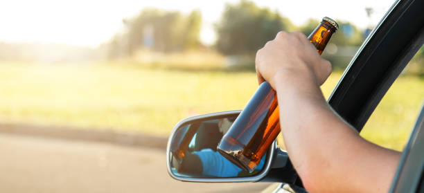 Car driver holding a bottle of beer stock photo