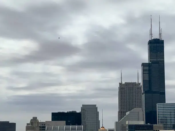 Photo of Airplane flying in a cloudy, overcast sky over the Chicago Loop skyline