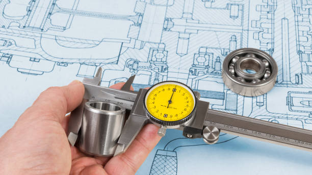 measurement of a steel bushing diameter with caliper in human hand. ball bearing on technical drawing of combustion engine. drafting - drafting plan engineering planning imagens e fotografias de stock