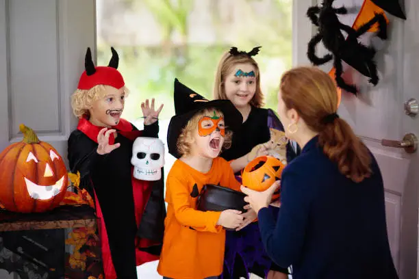 Photo of Kids trick or treat. Halloween. Child at door.