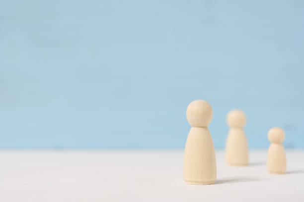 istock Three faceless wooden toy figures stand apart from each other with copy space. 1179451293