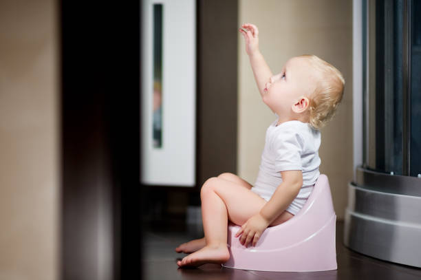 istock baby sits on a piss-pot in the bathroom and pulls her hand up 1179454778