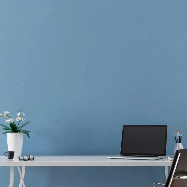 Workdesk with decoration in front of empty light blue plaster  wall with copy space. 3D rendered image.